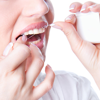 Young woman flossing teeth , studio shot