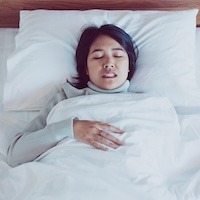 Asian Woman Sleeping On Bed And Grinding Teeth